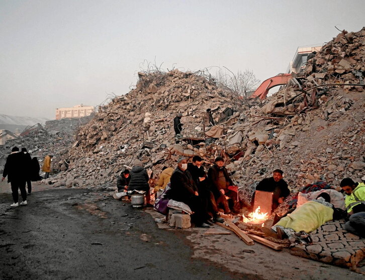 Una familia intenta calentarse entre las ruinas en la ciudad de Kahramanmaras.
