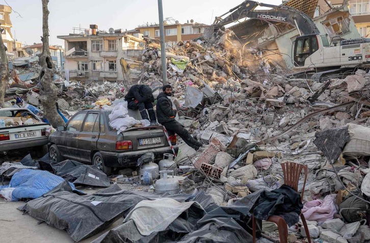 Dos hombres junto a los escombros de un edificio destruido en Hatay. 
