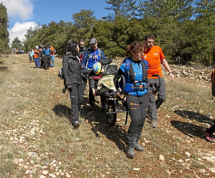 Entre cinco y seis personas se encargan de transportar la silla Joëlette por el monte.Fotografía: Kike Gómez 