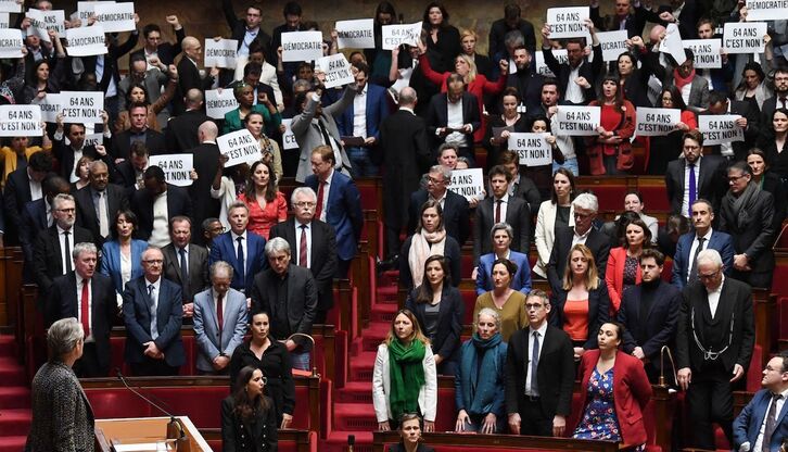 Los miembros de la coalición de izquierda NUPES sostienen pancartas contra la reforma durante una intervención de la primera ministra Élisabeth Borne en la Asamblea Nacional francesa..