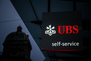 Imagen de una sucursal de UBS delante de la fachada del Parlamento suizo.