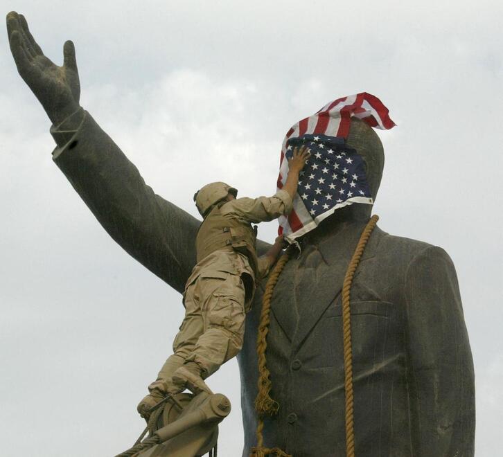Un marine estadounidense cubre la cara de una estatua de Saddam Husein con una bandera de EEUU, en abril de 2003.