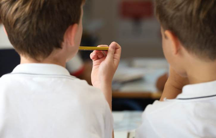 Un niño sostiene un lápiz en clase.
