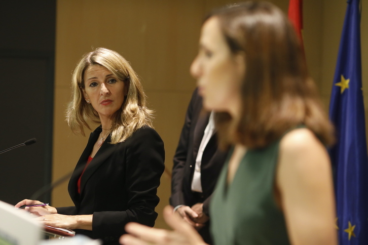 Yolanda Díaz (líder de Sumar) mira a Jone Belarra (secretaria general de Podemos) en un acto conjunto como ministras del Gobierno español.
