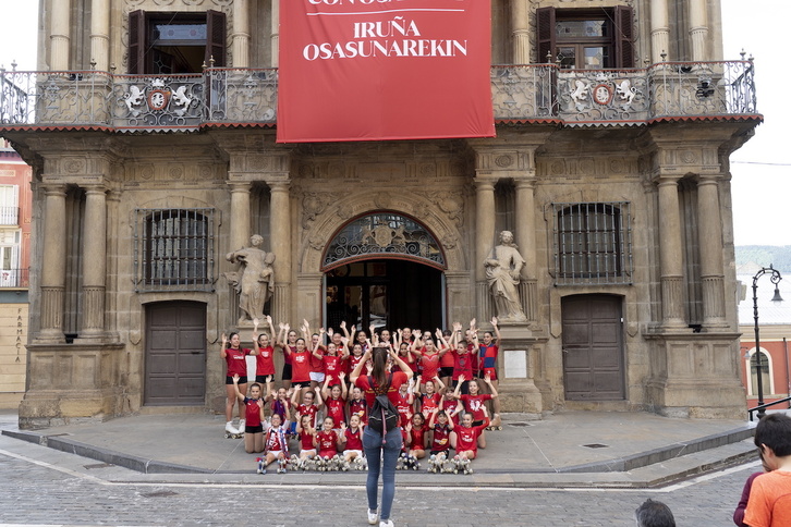 Unos niños y niñas se fotografían en la Casa Consistorial de Iruñea donde cuelga una camiseta gigante de Osasuna.