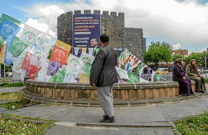 Un hombre pasa ante banderas electorales del HDP y un cartel del presidente, Recep Tayyip Erdogan, en el histórico barrio Sur de Diyarbakir, en Kurdistán Norte.