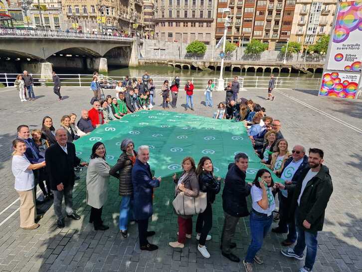 Ikerketa bultzatu dadila aldarrikatzeko bandera erraldoia zabaldu dute Bilbon hainbat erakundeetako ordezkariek.