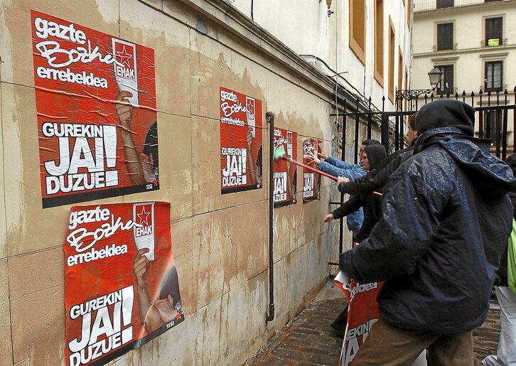 Jóvenes pegan carteles en las paredes durante la campaña electoral de las autonómicas de 2005.