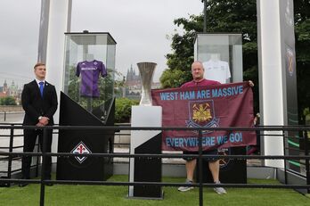 Un aficionado del West Ham posa con la copa de la Conference League.
