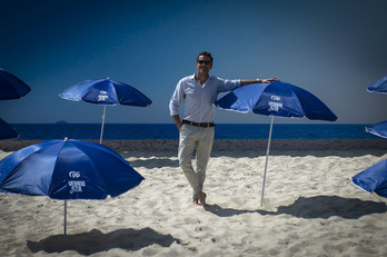 Borja Sémper posa en la falsa playa en la que ha dado su rueda de prensa. El mar del fondo es una fotografía. 