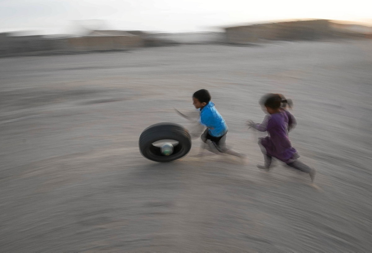 Niños jugando tras una rueda en las calles de Auserd.