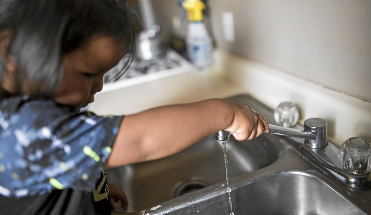 Neska navajo bat etxeko ur txorrota irekitzen. DigDeep's Navajo Water Project