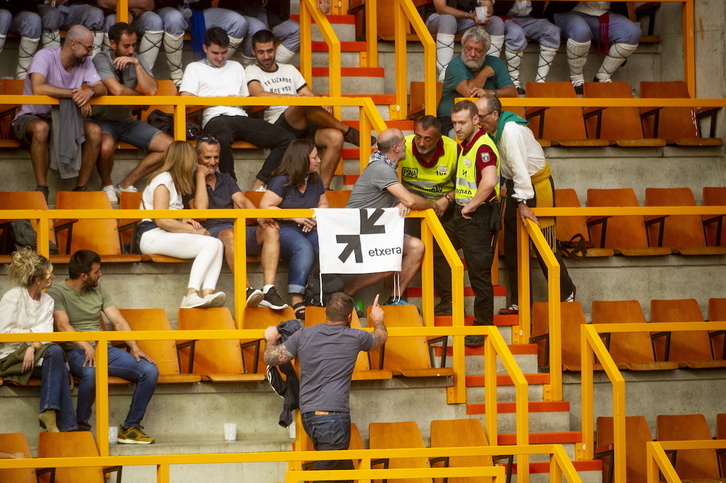 El personal de seguridad habla con el aficionado que había colocado la bandera de Etxera.