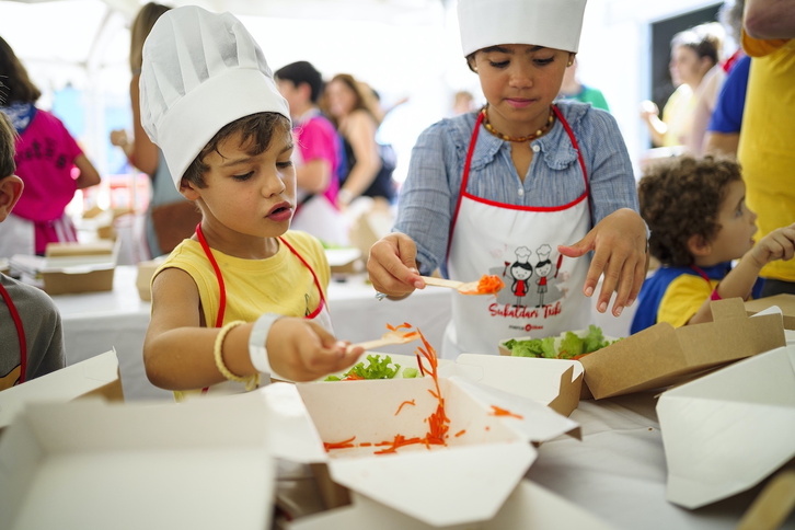 Un niño y una niña elaborando sus ensaladas en el «gastrotxiki» del Arenal.