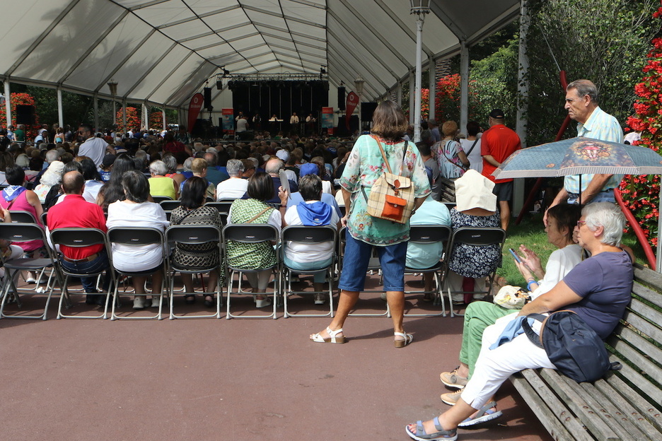 Con la carpa llena, no queda otra que el paraguas para protegerse del sol.