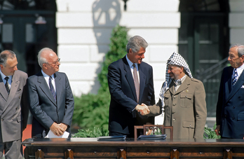 Bill Clinton estrecha la mano de Yasser Arafat ante la mirada de Yitzhak Rabin en la firma de los Acuerdos de Oslo.