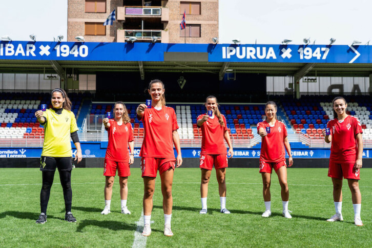 Jugadoras del Eibar posan con los abonos sobre el césped de Ipurua.