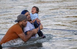 El venezolano Yonder Urbina (centro) sujeta a la bebé Olga, de un año, junto a su primo Oskeivys González, en el Río Grande.