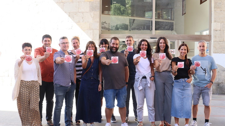 Guraso elkarteko, saltokietako eta Tolosako Udaleko ordezkariak, pegatina identifikagarria erakusten.