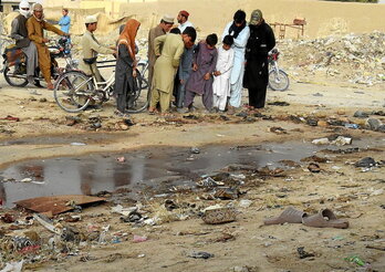 Varias personas observan los restos de la explosión en Mustang, en Baluchistán.