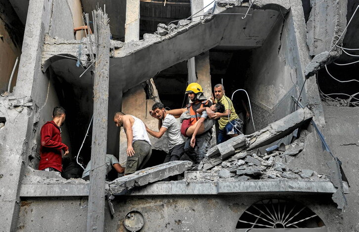 Miembros de la defensa civil palestina llevan un niño muerto en el bombardeo de viviendas en Jan Yunis.