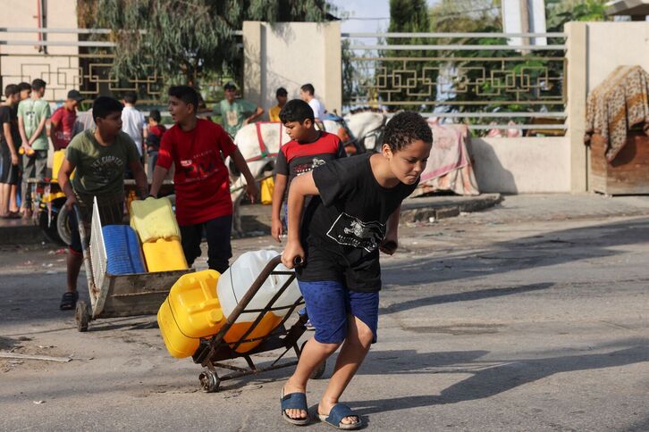 Jóvenes palestinos trasladan garrafas de agua en Rafah.