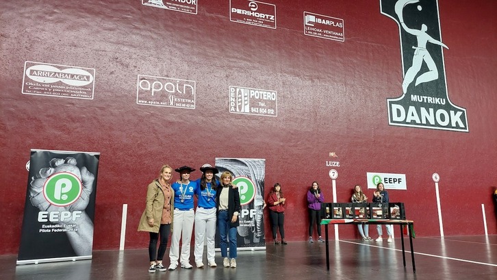 Arakistain eta Lizardi txapela jantzita, Mutrikuko Udaleko kultura zinegotzi Saioa Elezgarai eta Gipuzkoako Pilota Federazioko presidente Itziar Leterekin. 