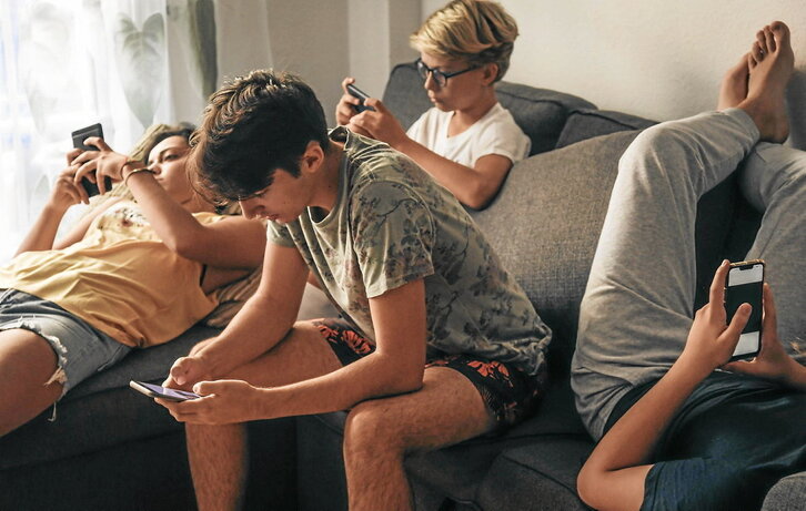 Nerabe kuadrilla bat etxe ingurune batean telefono mugikorrarekin.