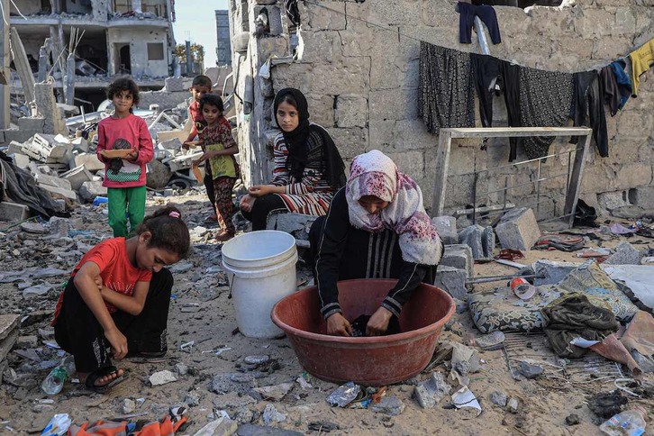 Una mujer palestina hace la colada en un barreño en medio de las ruinas de Rafah, al sur de Gaza.