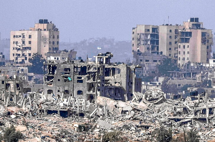 Banderas israelíes ondeando sobre edificios destruidos dentro de la Franja de Gaza.