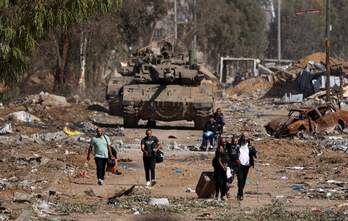 Palestinos heridos huyen delante de un tanque israelí