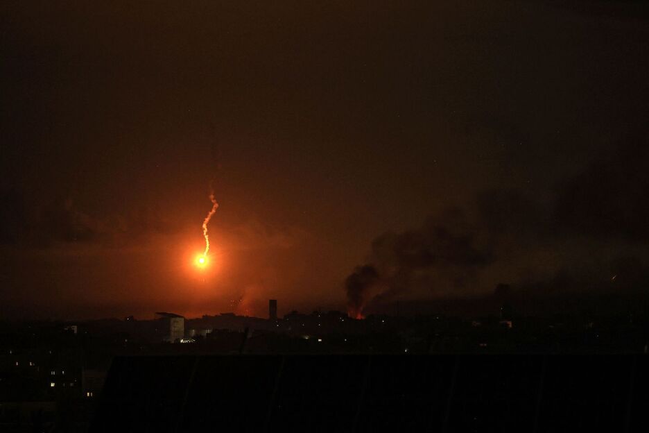 Una imagen tomada desde Rafah muestra una bengala iluminando el cielo mientras ondea humo tras el bombardeo israelí de Jan Yunis. Una imagen tomada desde Rafah muestra una bengala iluminando el cielo mientras ondea humo tras el bombardeo israelí de Jan Yunis.