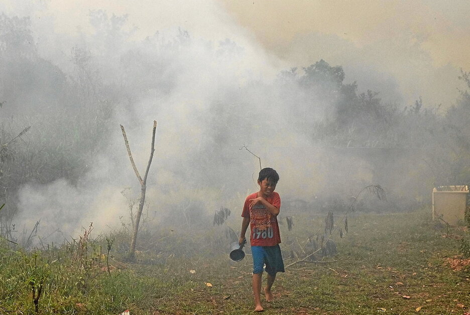 Un niño escapa del humo en el incendio de Ogan Ilir, Sumatra del Sur. Un niño escapa del humo en el incendio de Ogan Ilir, Sumatra del Sur.