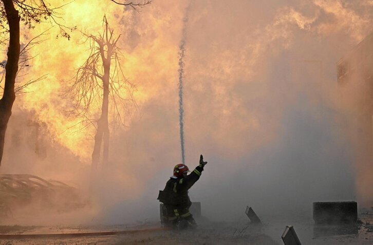 Ukrainar suhiltzaile bat, atzoko misil erasoek sortutako sute bat itzaltzen saiatzen.