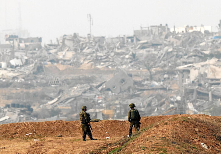 Bi soldadu israeldar, suntsitutako etxeen aurrean, Gazako hegoaldean.