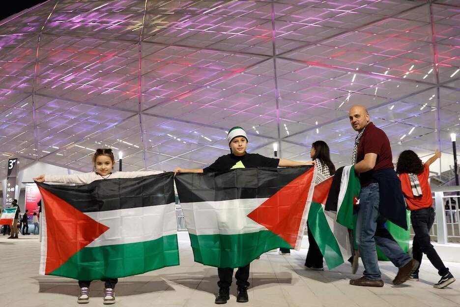 Bi ume Palestinako banderekin Dohako Al-Rayyan zelaiaren kanpoaldean. Bi ume Palestinako banderekin Dohako Al-Rayyan zelaiaren kanpoaldean.