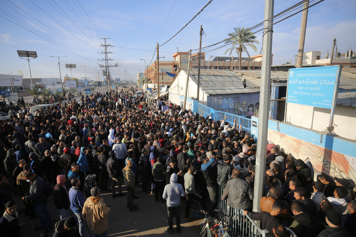 Dozenaka palestinar UNRWAk banatzen duen irina jasotzeko zain, Gazako Zerrendan, abenduan.
