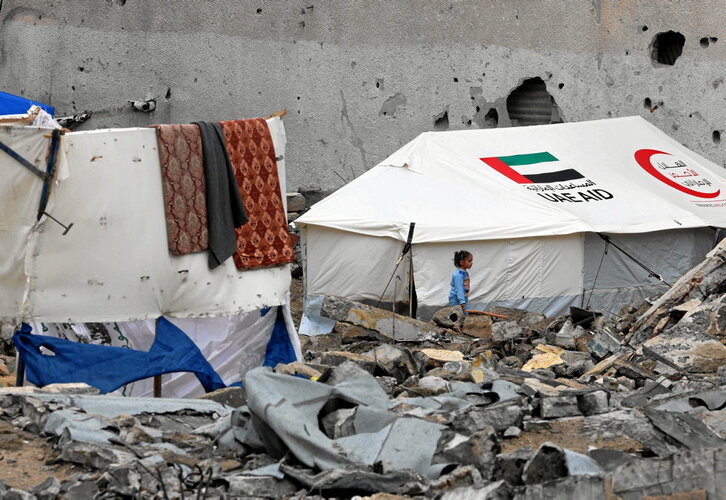 Una niña entre escombros, en Rafah, junto a una tienda de la Media Luna Roja de Emiratos Árabes Unidos.