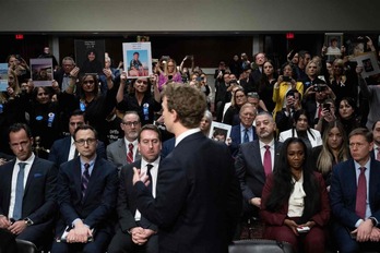 Parte del público muestra a Zuckerberg, de espaldas, imágenes de víctimas de abusos en redes sociales.  