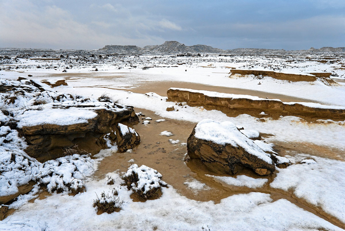 Bloques de antiguos estratos de arenisca sobre las arcillas nevadas.