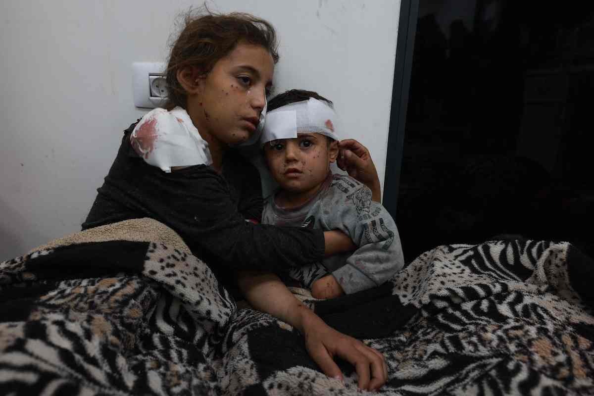 La niña Somay al-Najar consuela a su hermano Yamen en el hospital. (Mohamed ABED/AFP)