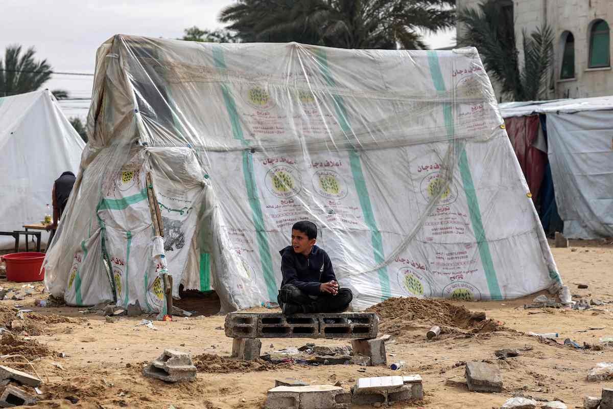 Un niño palestino, junto a una tienda en un campo de desplazados en Rafah. (Mohamed ABED/AFP)