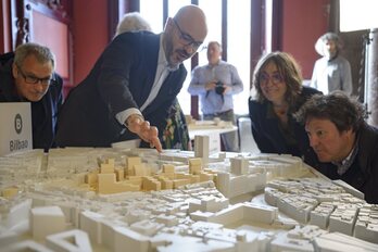 Integrantes del equipo ganador observan la maqueta del proyecto que han presentado.