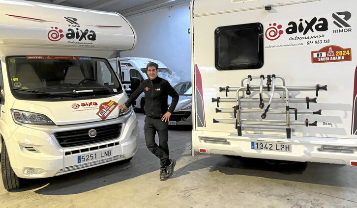 Marino Zulet posa con la elástica rojilla en el desierto arábigo, con un trofeo del Dakar y junto a algunas de las autocaravanas que desplazó al rally el pasado enero.