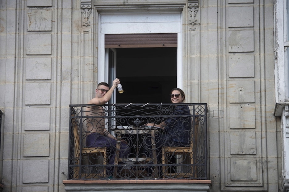 Dos personas saludan al fotógrafo desde un balcón en Gasteiz.