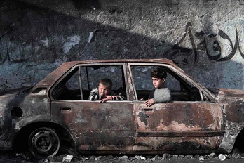 Dos niños palestinos en un coche calcinado por los ataques israelíes en Rafah.