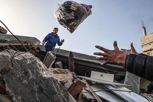 Gazatíes rescatan enseres de entre los escombros. 