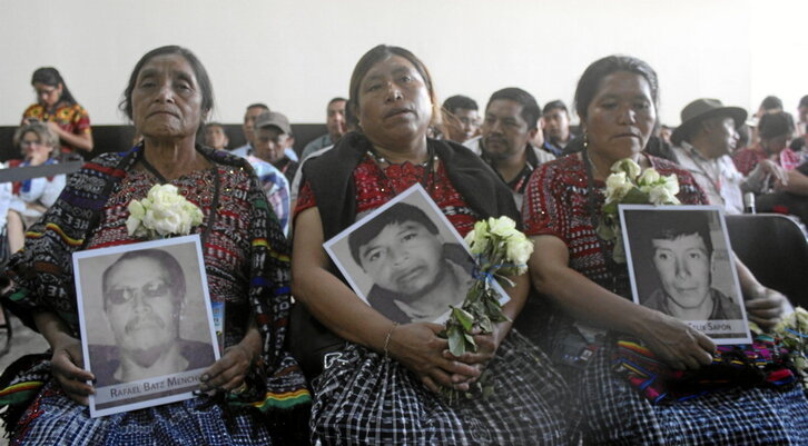 Mujeres indígenas muestran los retratos de sus familiares a los que el Ejército mató.