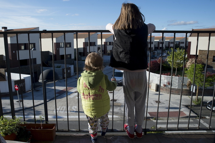 Dos txikis observan la calle, vetada por el confinamiento, desde el balcón de su hogar.