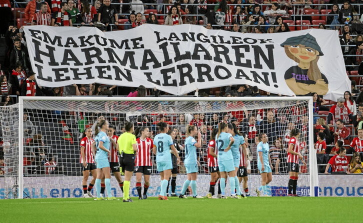 Jugadoras del Athletic y Barça se preparan para un córner mientras la grada muestra una pancarta conmemorativa del 8M.